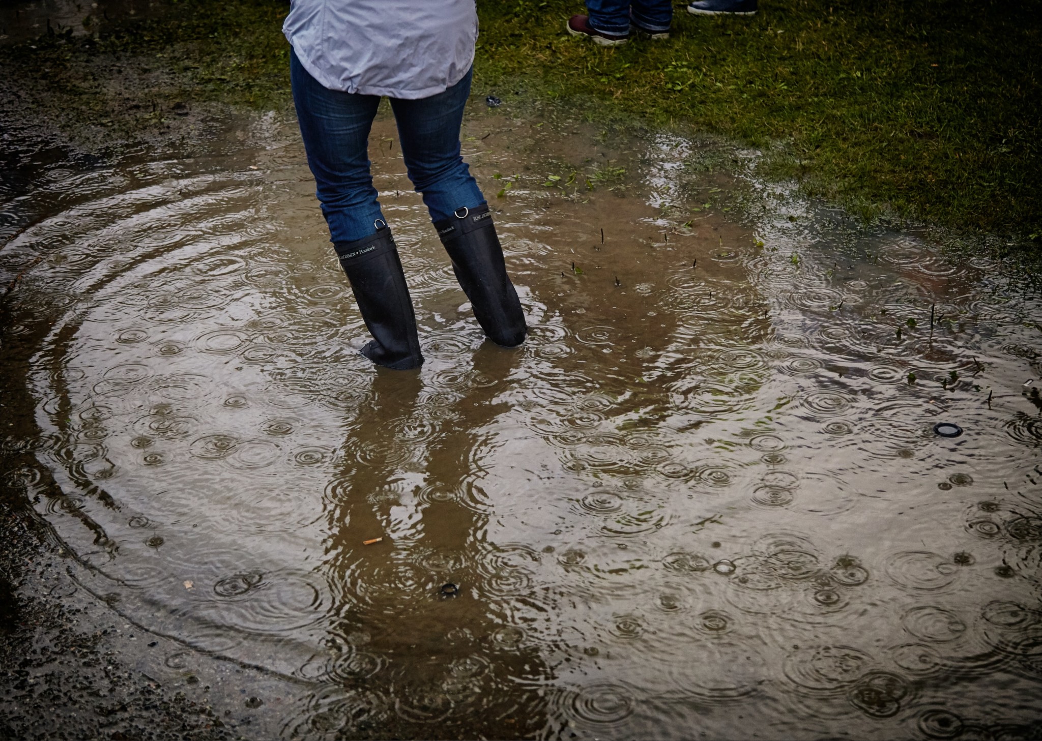 woman standing in puddle outside of home that has experienced spring water damage