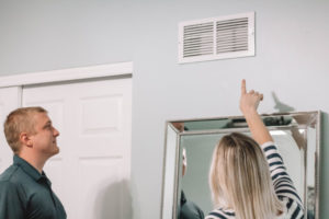 Woman pointing out dusty ducts to Sams cleaning technician.