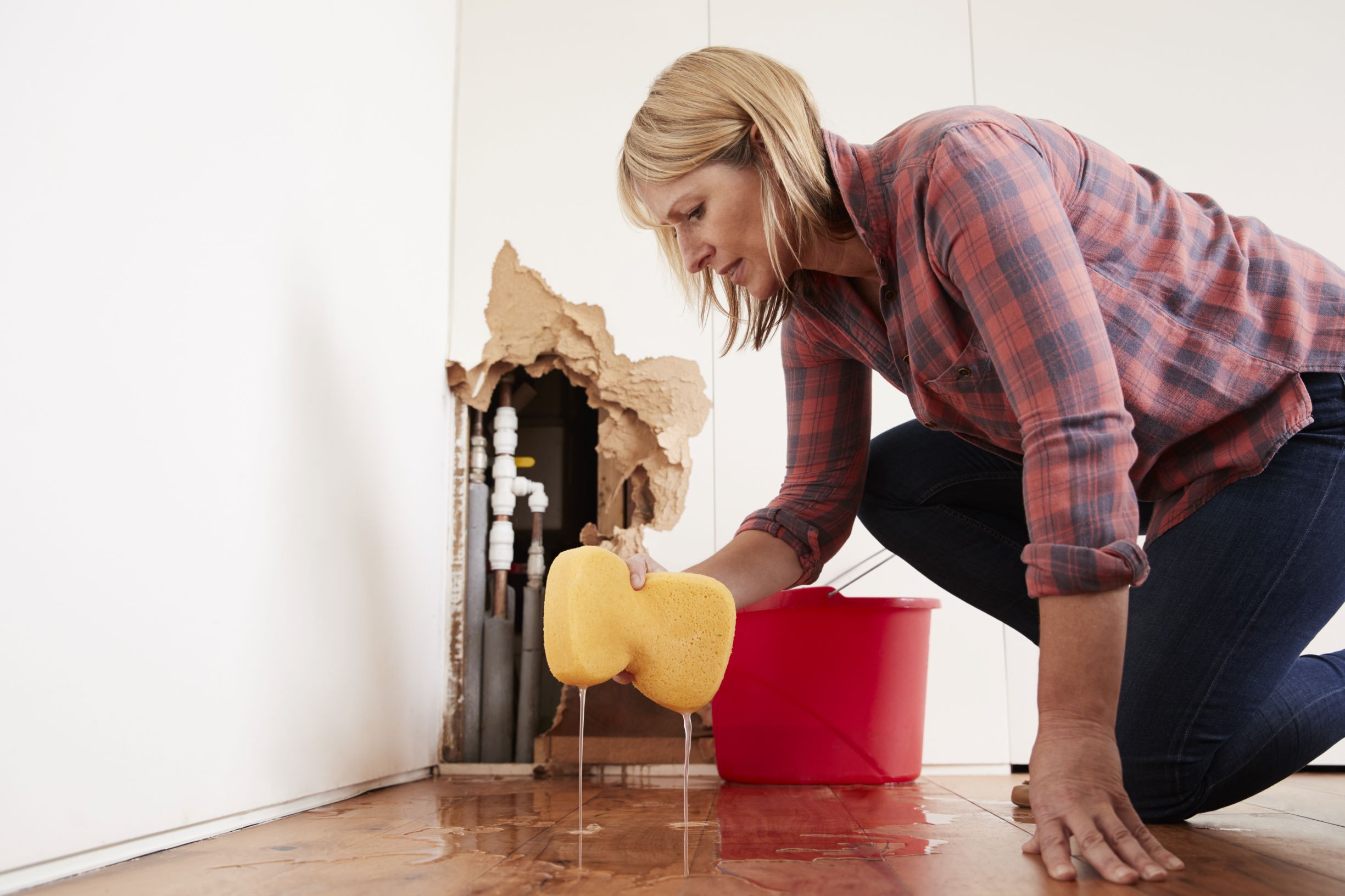 Woman cleaning up after a water pipe bursts.