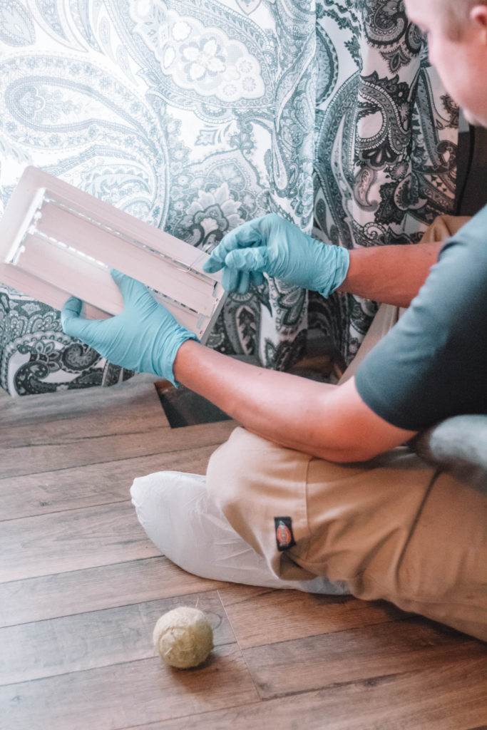 man inspecting vents while performing air duct cleaning services